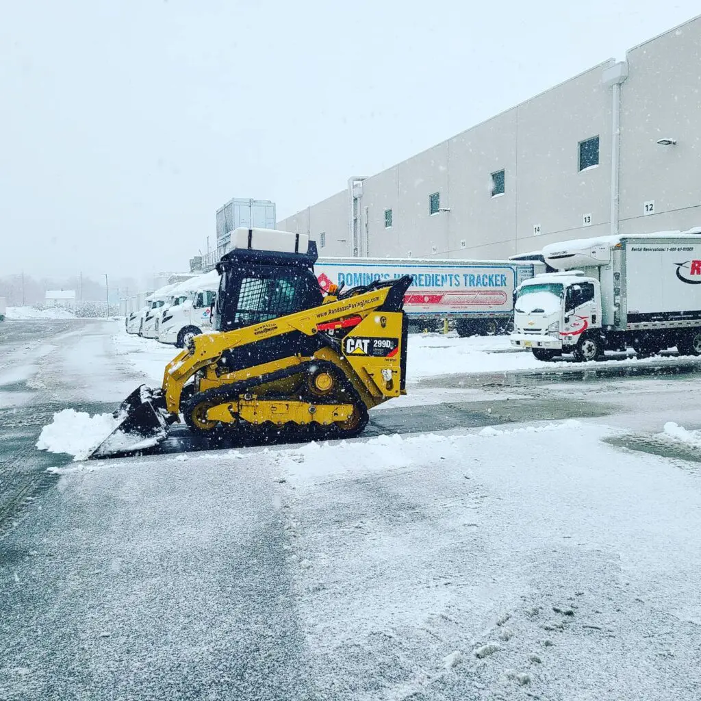 A JCB machine picking up the snow from the street